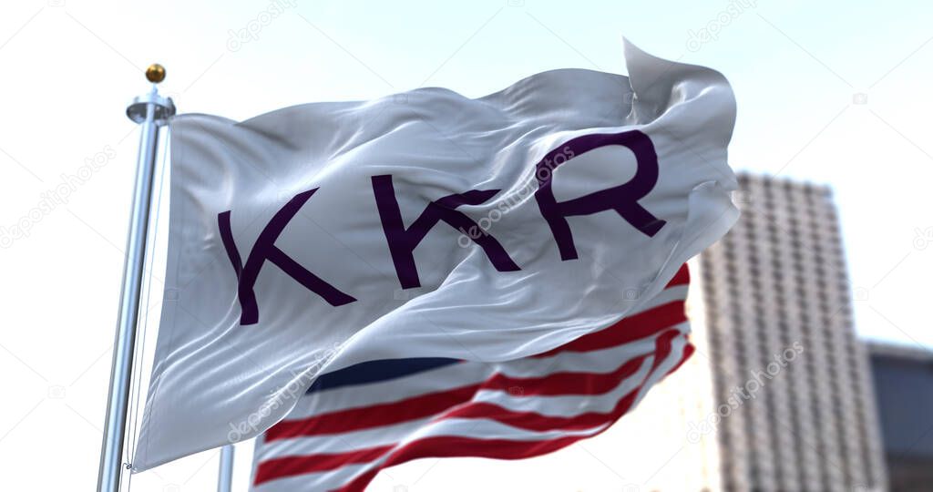 New York, USA, November 2021: The flag With KKR logo waving in the wind with the American national flag blurred in the background