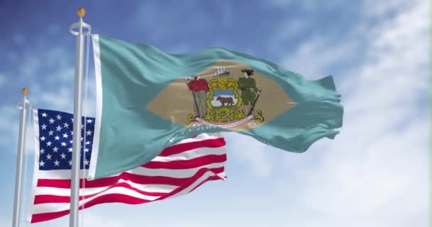 特拉华州的国旗与美利坚合众国国旗一同飘扬 在背景上有一个晴朗的天空 4K无缝圈 — 图库视频影像