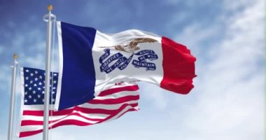 Iowa eyalet bayrağı, Amerika Birleşik Devletleri bayrağıyla birlikte dalgalanıyor. Arka planda açık bir gökyüzü var. Iowa, ABD 'nin orta batısında bulunan bir eyalettir.