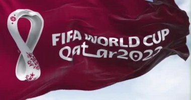 Doha, Katar, Nisan 2022: 2022 Fifa Dünya Kupası logosu rüzgarda dalgalanan bir bayrak. Etkinlik 21 Kasım - 18 Aralık 2022 tarihleri arasında Katar 'da gerçekleşecek.
