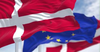Detail of the national flag of Denmark waving in the wind with blurred european union flag in the background on a clear day. Democracy and politics. European country. Selective focus.