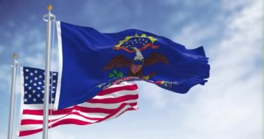 Kuzey Dakota eyalet bayrağı, Amerika Birleşik Devletleri bayrağıyla birlikte dalgalanıyor. Arka planda açık bir gökyüzü var. Kuzey Dakota, Orta Batı 'da bulunan bir eyalettir.