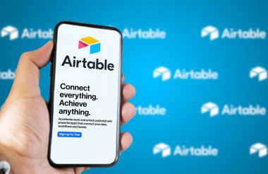 San Francisco, CA, ABD, Mayıs 2022: Erkek el, Airtable şirketinin web sayfası ekranda. Arka planda, logo Airtable bulanıklaştı ve tekrarlandı. Airtable bir bulut işbirliği hizmetidir.