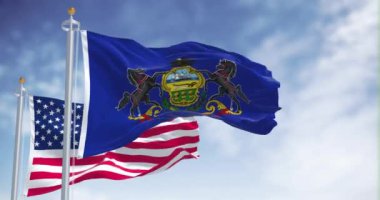 Amerika Birleşik Devletleri bayrağıyla birlikte dalgalanan kusursuz Pennsylvania bayrağı. Arka planda açık bir gökyüzü var. Pennsylvania, ABD 'nin kuzeydoğusunda yer alan bir eyalettir.