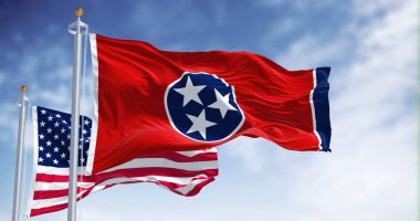 The Tennessee state flag waving along with the national flag of the United States of America. Tennessee is a state in the Southeastern region of the United States