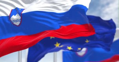 Seamless slow motion loop of the national flag of Slovenia waving in the wind with blurred european union flag in the background on a clear day. Democracy and politics. European country. Selective focus.