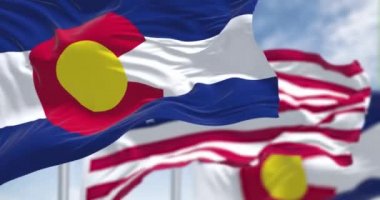 Kolorado eyaletinin iki bayrağı Amerika Birleşik Devletleri bayrağıyla birlikte dalgalanırken, ağır çekimde kusursuz bir döngü. Arka planda açık bir gökyüzü var..