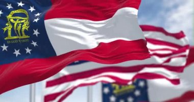 Amerika Birleşik Devletleri bayrağıyla birlikte sallanan iki Georgia bayrağıyla ağır çekimde kusursuz bir döngü. Arka planda açık bir gökyüzü var..