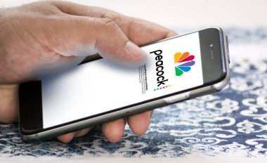 New York, ABD, Mayıs 2022: ekranda Peacock Tv mobil uygulaması olan bir telefonu tutmak. Peacock, NBCUniversal tarafından işletilen bir Amerikan video yayınlama servisidir.