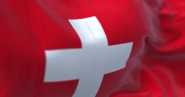 Close-up view of the swiss national flag waving in the wind. Switzerland is a landlocked country located in Europe. Fabric textured background. Selective focus. Seamless loop in slow motion