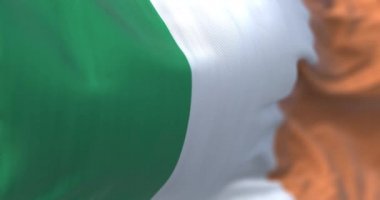 Close-up view of the irish national flag waving in the wind. Ireland is an island in the north-western Europe. Fabric textured background. Selective focus. Seamless loop in slow motion