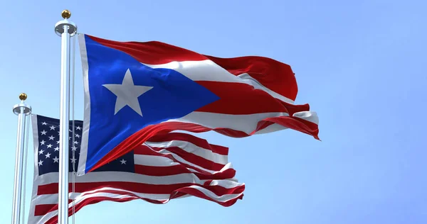 Flag of Puerto Rico waving in the wind with the United States flag on a clear day. Puerto Rico is a Caribbean island and unincorporated territory of the United States