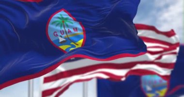 Guam bayrakları açık bir günde ABD bayrağıyla rüzgarda sallanıyor. Guam, Amerika Birleşik Devletleri 'nin batı Pasifik Okyanusu' nda yer alan bir bölgesidir. Yavaş çekimde kusursuz döngü