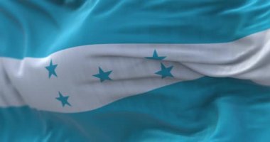 Rüzgarda dalgalanan Honduras ulusal bayrağının yakın çekim görüntüsü. Honduras Cumhuriyeti bir Orta Amerika devletidir. Kumaş desenli arka plan. Seçici odaklanma. Yavaş çekimde kusursuz döngü