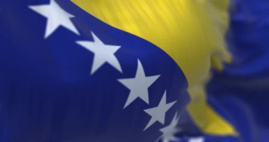 Bosna-Hersek bayrağının rüzgarda dalgalandığı yakın çekim görüntüsü. Bosna-Hersek güneydoğu Avrupa 'da bir ülkedir. Kumaş desenli arka plan. Seçici odaklanma. Yavaş çekimde kusursuz döngü