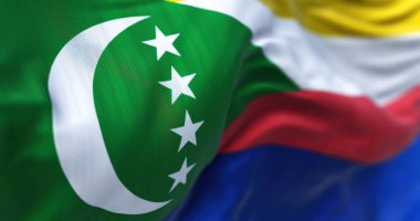Comoros ulusal bayrağının rüzgarda dalgalanmasını yakından izliyoruz. Comoros Birliği, Hint Okyanusu 'nda bir takımada ülkesidir. Kumaş desenli arka plan. Seçici odak