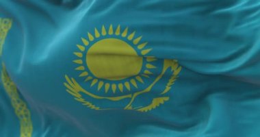 Rüzgarda dalgalanan Kazakistan ulusal bayrağının yakın çekim görüntüsü. Kazakistan Cumhuriyeti kıtalararası bir devlettir. Kumaş desenli arka plan. Seçici odaklanma. Yavaş çekimde kusursuz döngü