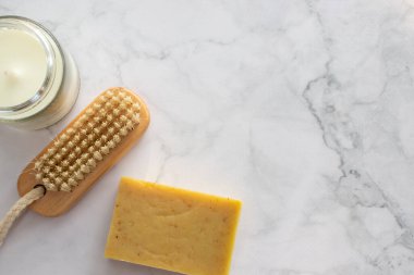 Kişisel bakım, güzellik ve rahatlama için bir takım ürünler. Aroma mumu, fırça, organik bitkisel sabun, beyaz üzerine yüz süngeri. Mermer arka plan. Masada hijyenik aksesuarlar var. Üst görünüm, düz görünüm, kopyalama alanı