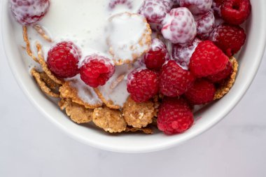 Yoğurtlu mısır gevreği ve mermer masa arkasında taze ahududu. Sağlıklı diyet kahvaltısı. Üst görünüm, düz görünüm, kopyalama alanı 
