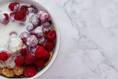 Yoğurtlu mısır gevreği ve mermer masa arkasında taze ahududu. Sağlıklı diyet kahvaltısı. Üst görünüm, düz görünüm, kopyalama alanı 