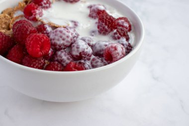 Yoğurtlu mısır gevreği ve mermer masa arkasında taze ahududu. Sağlıklı diyet kahvaltısı. Üst görünüm, düz görünüm, kopyalama alanı 
