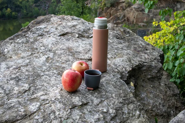 Beige Thermos Bottle Cup Tea Coffee Red Apple Rock River Imágenes de stock libres de derechos