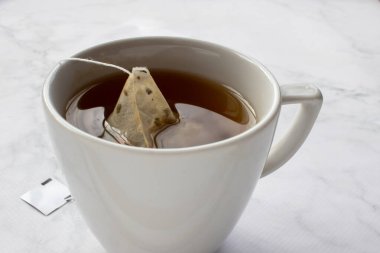 Masada bir fincan çay. Beyaz mermer arka planda yeşil bitki çayı. Üst görünüm, boşluğu kopyala. Geleneksel çay saati