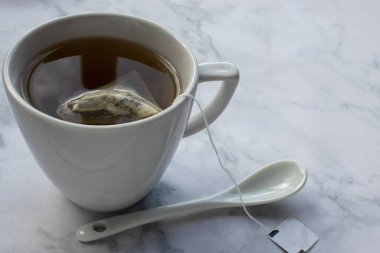 Masada bir fincan çay. Beyaz mermer arka planda yeşil bitki çayı. Üst görünüm, boşluğu kopyala. Geleneksel çay saati