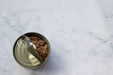 Beyaz mermer mutfak masasında doğranmış ton balığı ve yağlı teneke kutu. Teneke kutuda balık konservesi. Üst görünüm, alanı kopyala