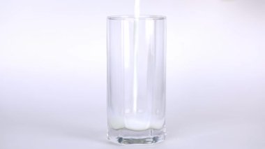 milk is poured on a light background with a transparent glass