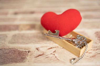 Bronze house key and red country fabric heart  old wood, Valentines Day, real estate and home concept background with wooden painted copy space.