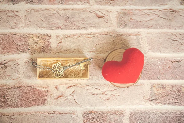 Bronze house key and red country fabric heart  old wood, Valentines Day, real estate and home concept background with wooden painted copy space.