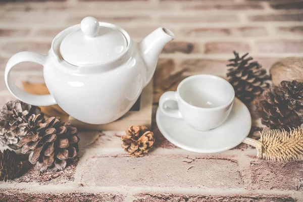 Tea concept, white teapot with white tea cup with dry leaves on wooden background, view from side. organic product from the nature for healthy with traditional.