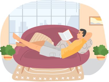 Genç çocuk kanepede uzanıyor ve ilginç kitaplar okuyor. Hafta sonunu evde geçirip rahatlıyor.