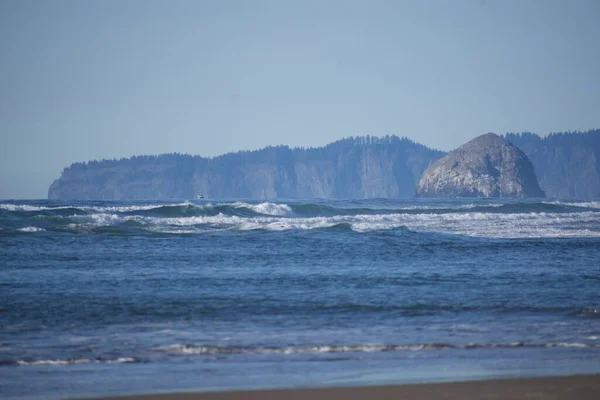 水が飛び散る大きな波 背景に森がある島 — ストック写真
