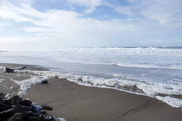 sandy beach with big ocean waves, water splashes