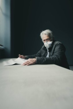 Karantinaya alınan son sınıf öğrencisi evde tek başına oturuyor ve gazetede COVid-19 hakkında korkunç haberler okuyor. Ameliyat maskesi takıyor.