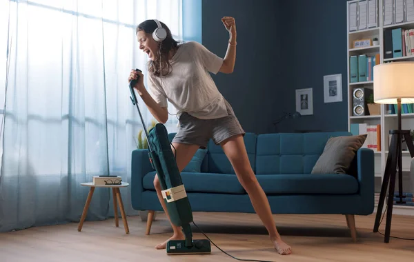 一个快乐的女人在打扫她的家 她正在用吸尘器作为话筒 — 图库照片