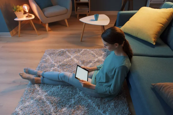 若い女性は自宅でリラックスし 彼女は床に座って 彼女のデジタルタブレットとオンラインで接続しています — ストック写真