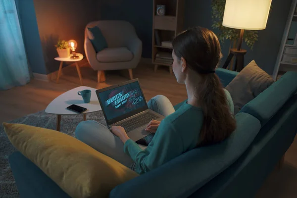 若い女性は家でリラックスし 彼女はソファの上で休んで 彼女のラップトップとオンラインで接続しています — ストック写真