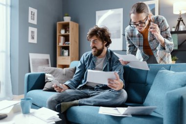 Şok olmuş genç çift evdeki faturalarını kontrol ediyor. Bütçeleriyle ilgili sorunları var.