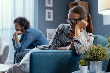 Evde kavga eden üzgün genç bir çift, kanepede oturup birbirlerini görmezden geliyorlar, ilişki sorunu kavramı.