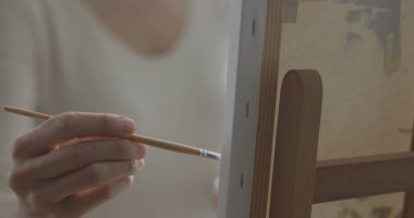 Stüdyosunda çalışan yaratıcı kadın boya fırçasıyla tuvale resim yapıyor.