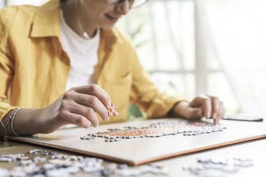 Evde masa başında oturan bir kadın bulmaca, eğlence ve oyun konseptini çözüyor.