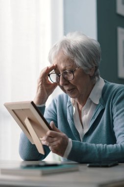 Kocasının yasını tutan üzgün kadın elinde bir resim tutuyor ve ağlıyor.
