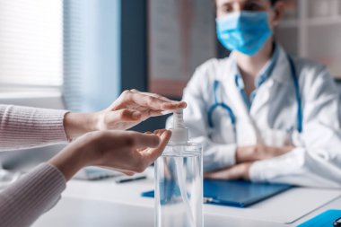 Hastanın ellerini antibakteriyel jel, koronavirüs önleyici kullanarak sterilize ediyor.
