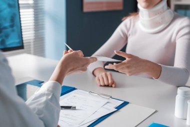 Profesyonel doktor boyun tasması olan bir hastaya tıbbi reçete yazıyor.