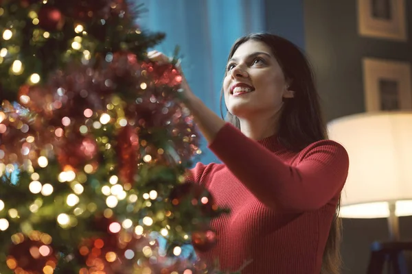 漂亮的女人在家里装饰着圣诞树 她挂着装饰品和浴盆 还有节日和庆祝的念头 — 图库照片