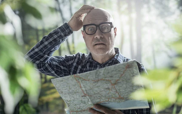 Worried tourist lost in the wilderness, he is checking a map