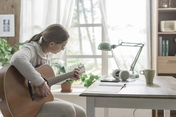 Ung Kvinna Sitter Bredvid Ett Skrivbord Hemma Och Spelar Gitarr — Stockfoto